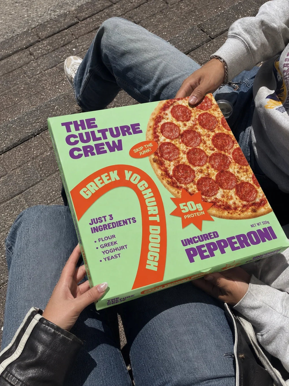 Someone sitting outside holding an Uncured Pepperoni pack